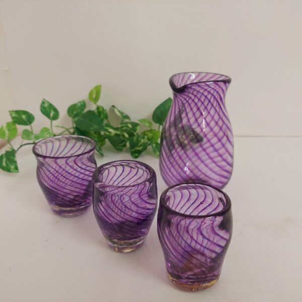 吹きガラスで作った酒器セットです。透明のがらすで作った徳利とぐい呑みに、緩くカーブして描かれた沢山の紫色の線が重なり合い、とても美しいです。