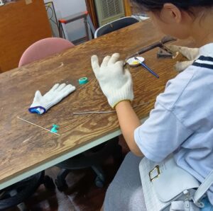 小学生がステンドグラス体験でハンダ付けをしています。