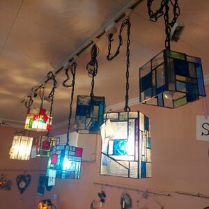 沢山のステンドグラスのキューブ型ペンダントランプをダクトレールに吊り下げて展示しています。