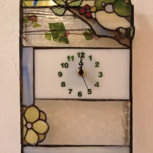 ステンドグラスの花と小鳥の時計です。下に黄色い花、中心にグリーンの文字の時計、上に赤い木の実を咥えた小鳥が可愛くチョコンと乗っている時計です。アーティストショップＡ＆ＭＯ2オリジナルの作品です